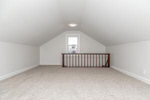 additional living space with light colored carpet and lofted ceiling