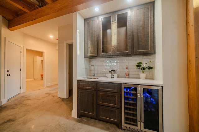 bar featuring backsplash, wine cooler, sink, and dark brown cabinets