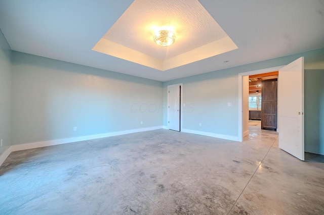 empty room featuring a tray ceiling, concrete flooring, and a textured ceiling