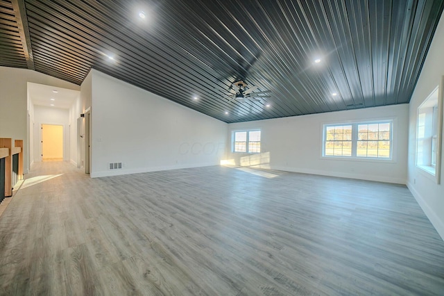 unfurnished living room with light hardwood / wood-style floors, vaulted ceiling, a wealth of natural light, and ceiling fan