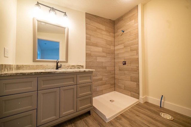 bathroom with tiled shower, wood-type flooring, and vanity