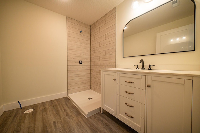 bathroom with hardwood / wood-style floors, vanity, wood walls, a shower, and a textured ceiling