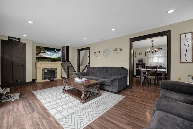 living room with a notable chandelier, dark hardwood / wood-style flooring, and a fireplace