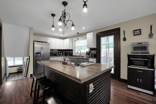 kitchen featuring hanging light fixtures, stainless steel appliances, a kitchen island, and white cabinetry