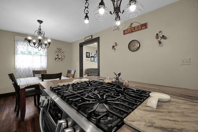 kitchen with an inviting chandelier, stainless steel gas range, dark hardwood / wood-style floors, light stone countertops, and decorative light fixtures