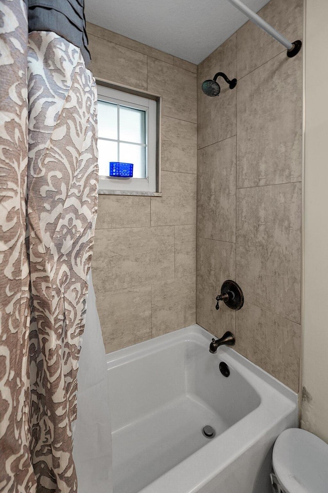 bathroom with shower / bath combination with curtain and toilet