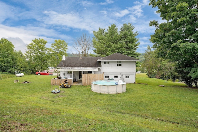 rear view of property featuring a yard and a pool side deck