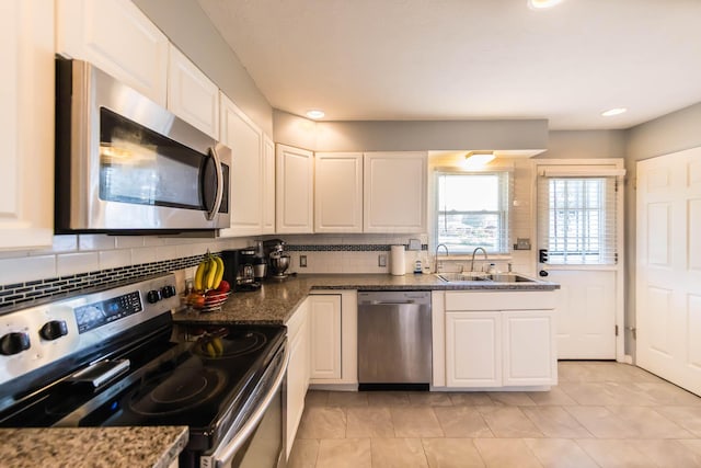 kitchen featuring white cabinets, sink, dark stone countertops, appliances with stainless steel finishes, and tasteful backsplash