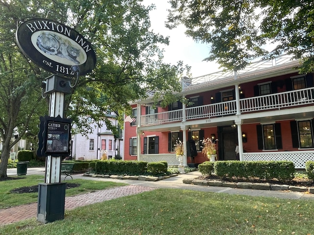 view of front of house with a balcony and a front lawn