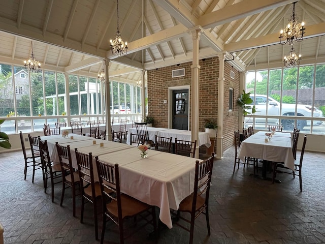 dining room with beam ceiling, plenty of natural light, high vaulted ceiling, and brick wall