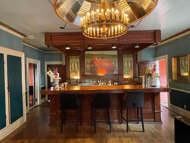 bar featuring dark hardwood / wood-style flooring, crown molding, and an inviting chandelier