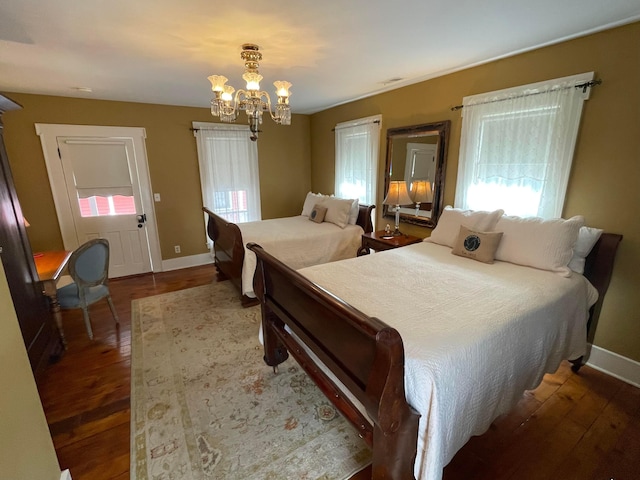 bedroom with dark hardwood / wood-style floors and a notable chandelier