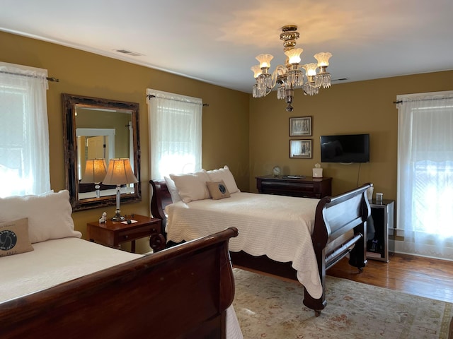 bedroom with an inviting chandelier and light hardwood / wood-style flooring