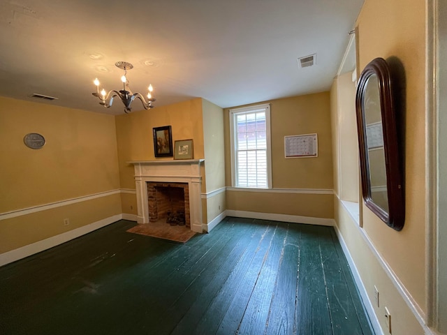 unfurnished living room featuring a chandelier, dark hardwood / wood-style floors, and a brick fireplace