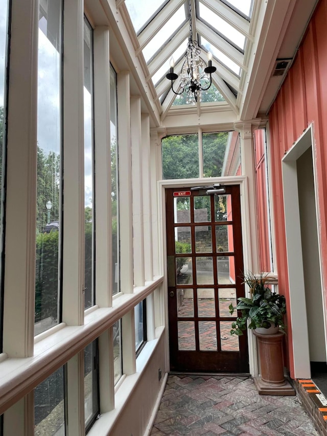 unfurnished sunroom with vaulted ceiling with skylight and a chandelier