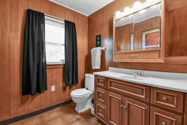 bathroom with vanity, wood walls, and toilet