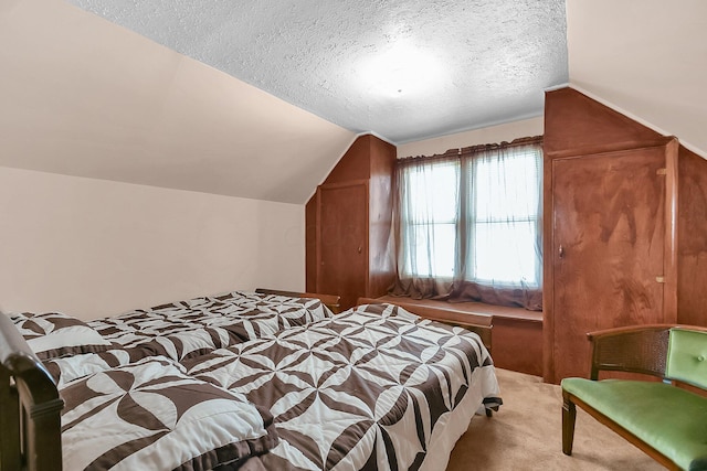 bedroom featuring vaulted ceiling, light colored carpet, and a textured ceiling