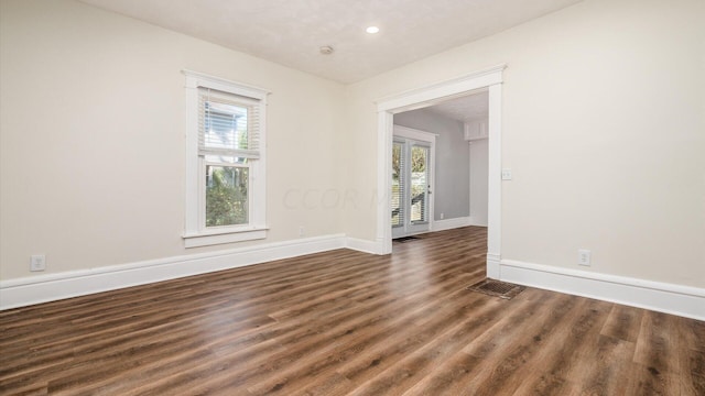 spare room with dark hardwood / wood-style flooring and plenty of natural light