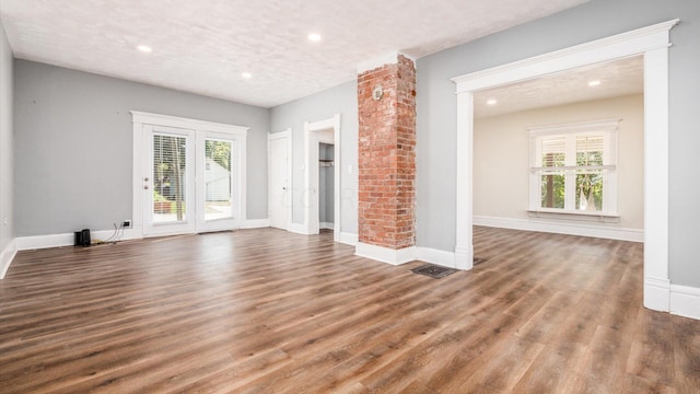 unfurnished living room with dark hardwood / wood-style flooring, a healthy amount of sunlight, and a textured ceiling