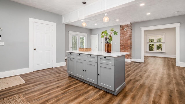 kitchen with gray cabinetry, a textured ceiling, dark wood-type flooring, a center island, and hanging light fixtures