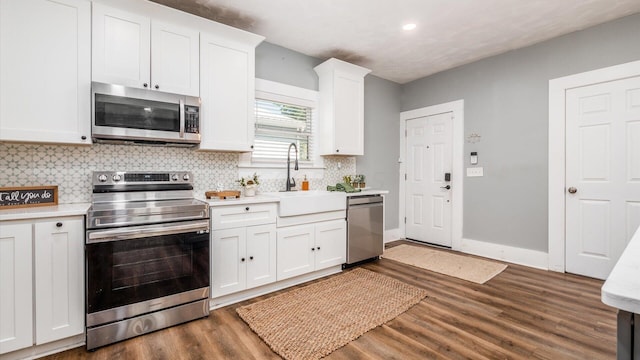 kitchen with appliances with stainless steel finishes, tasteful backsplash, dark wood-type flooring, sink, and white cabinetry