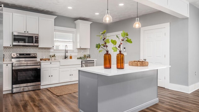 kitchen with appliances with stainless steel finishes, dark hardwood / wood-style flooring, white cabinetry, and sink