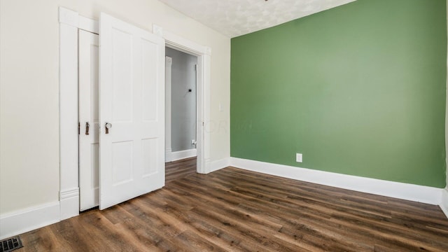 unfurnished bedroom featuring dark hardwood / wood-style floors, a textured ceiling, and a closet