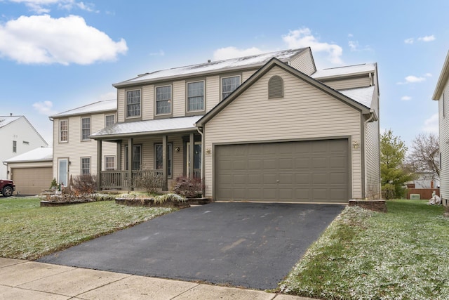 view of front of home featuring a garage, covered porch, and a front yard