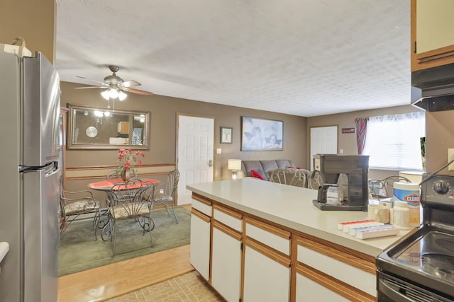 kitchen featuring white cabinets, ceiling fan, light wood-type flooring, black / electric stove, and stainless steel refrigerator