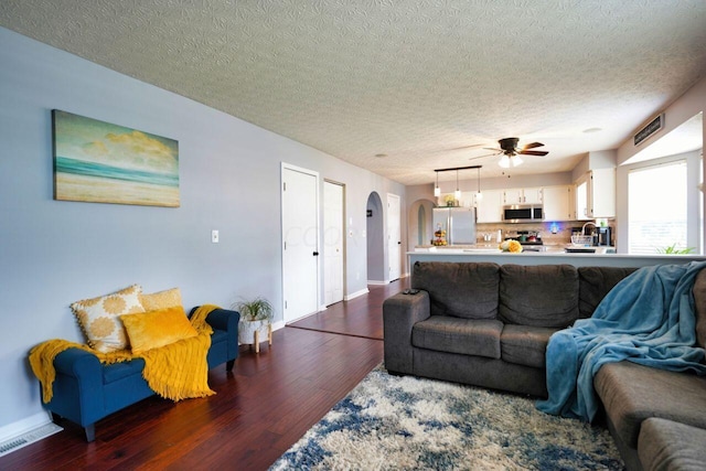 living room with ceiling fan, dark hardwood / wood-style flooring, and a textured ceiling