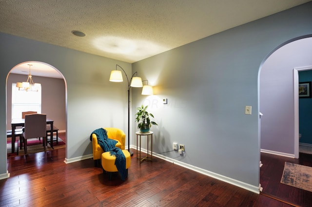 sitting room with dark hardwood / wood-style flooring, a notable chandelier, and a textured ceiling