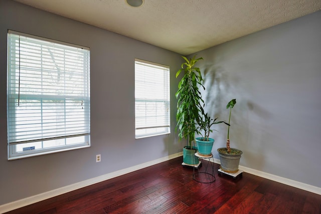 unfurnished room with dark wood-type flooring and a textured ceiling