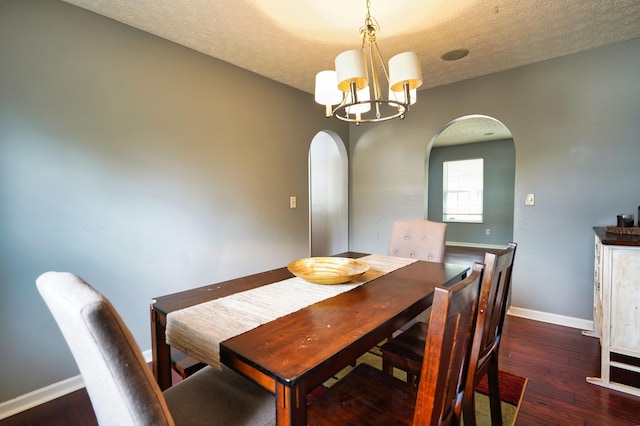 dining room with dark hardwood / wood-style floors, a notable chandelier, and a textured ceiling