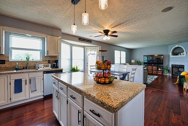 kitchen with dark hardwood / wood-style floors, sink, hanging light fixtures, a center island, and stainless steel dishwasher