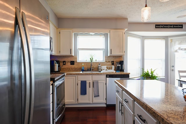 kitchen with hanging light fixtures, white cabinetry, appliances with stainless steel finishes, and sink