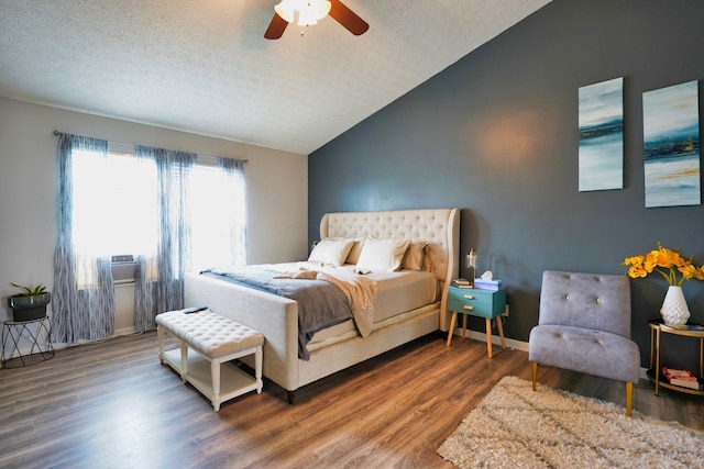 bedroom with ceiling fan, vaulted ceiling, dark hardwood / wood-style floors, and a textured ceiling