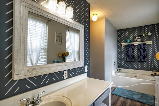 bathroom with hardwood / wood-style floors, sink, a textured ceiling, and a washtub