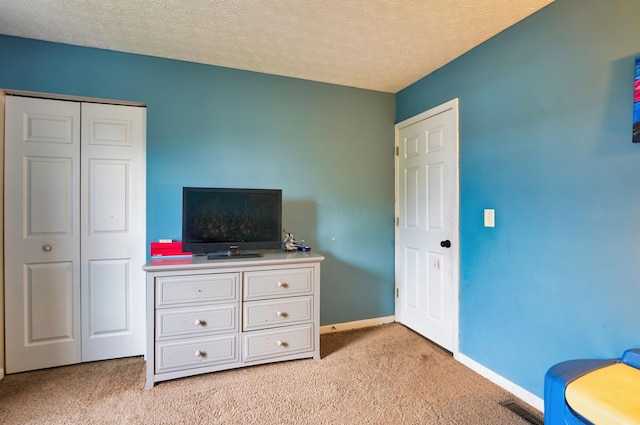 bedroom featuring light carpet, a closet, and a textured ceiling