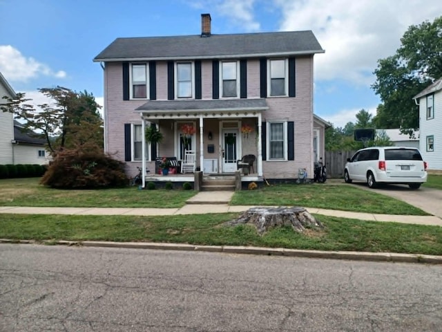 colonial home with a front yard and a porch