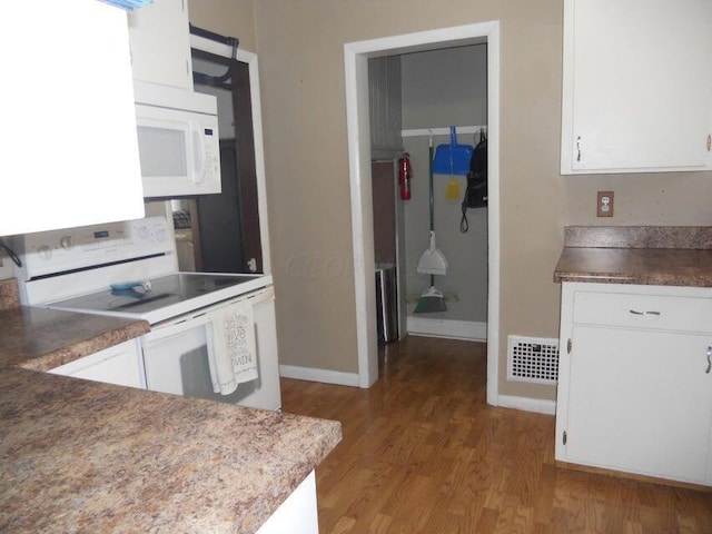 kitchen featuring white cabinets, light hardwood / wood-style floors, and white appliances