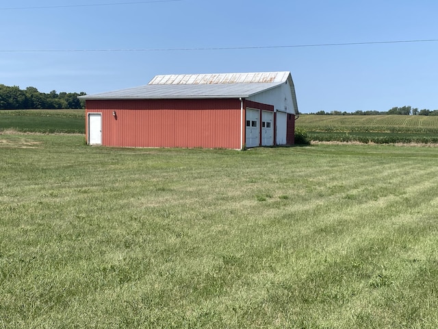 view of outbuilding featuring a lawn, a rural view, and a garage