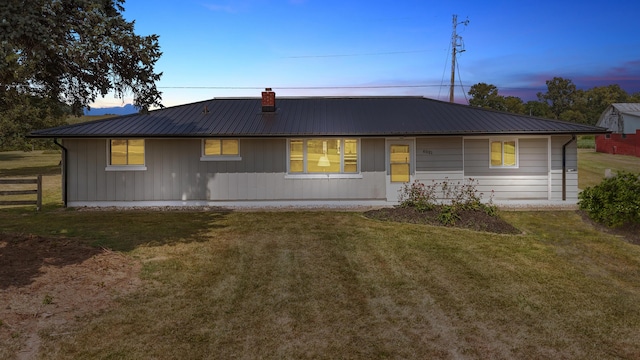 back house at dusk featuring a yard