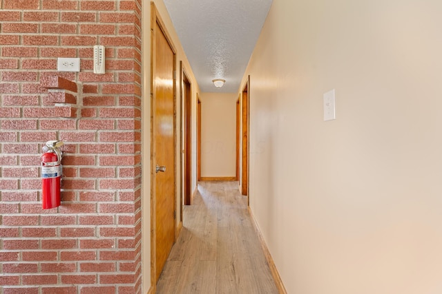 hallway with light hardwood / wood-style floors and a textured ceiling