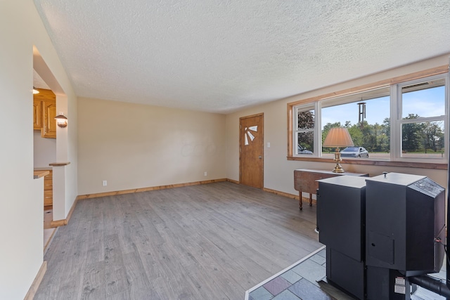 unfurnished living room featuring light hardwood / wood-style floors and a textured ceiling