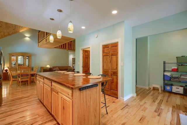 kitchen with a center island, decorative light fixtures, light hardwood / wood-style floors, and a kitchen bar