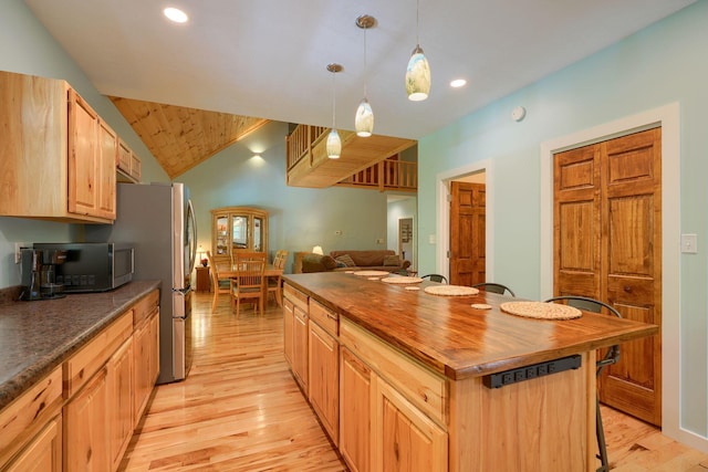 kitchen featuring appliances with stainless steel finishes, light wood-type flooring, vaulted ceiling, and hanging light fixtures