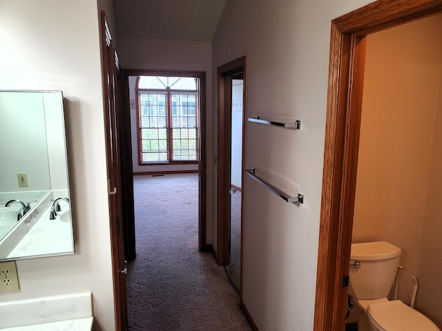 corridor featuring carpet floors and vaulted ceiling