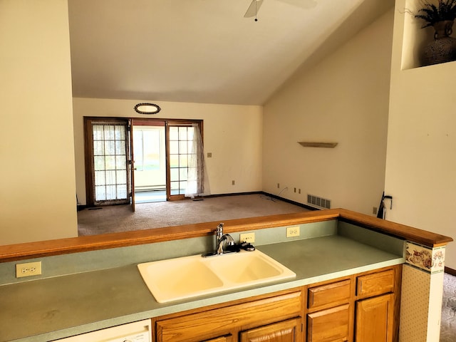 kitchen with ceiling fan, sink, carpet floors, and vaulted ceiling