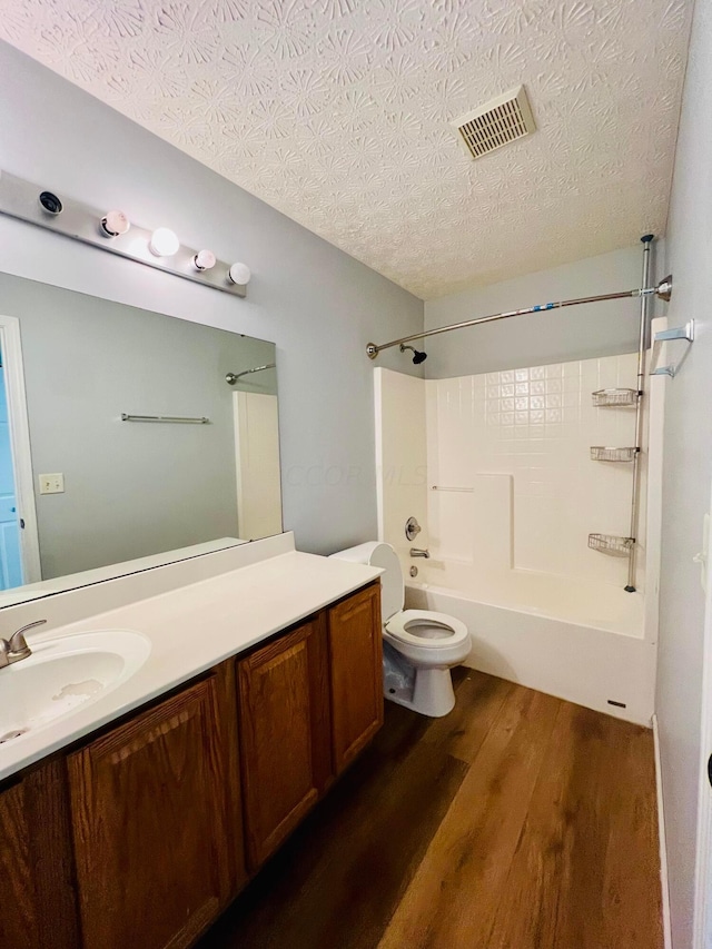 full bathroom featuring hardwood / wood-style floors, a textured ceiling, toilet, shower / washtub combination, and vanity