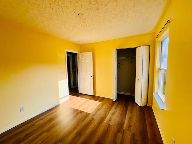 unfurnished bedroom with a textured ceiling, dark hardwood / wood-style flooring, and a closet